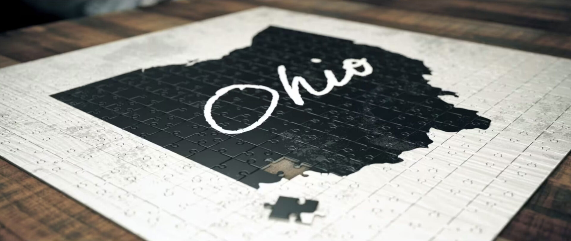 A black and white puzzle with the black pieces making the shape of the state of Ohio with white script