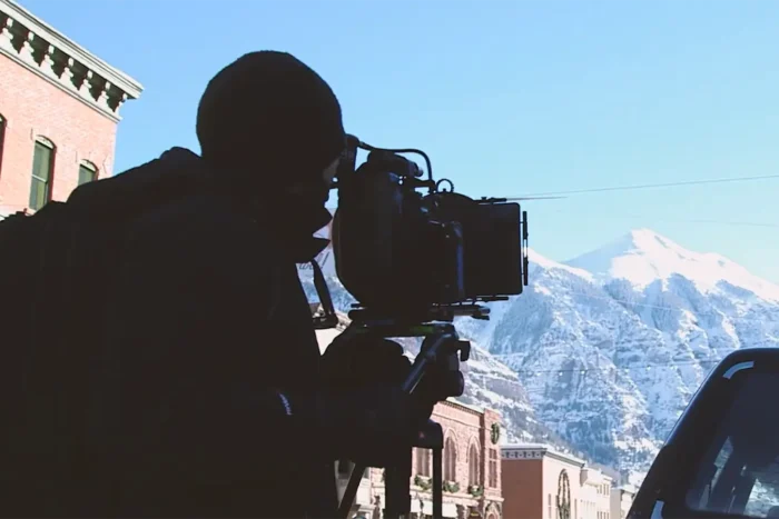 person shooting on a video camera in telluride colorado with mountain background