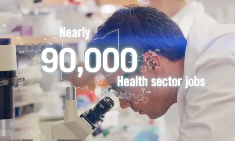 Nearly 90,000 health sector jobs text overlay on man looking through microscope for JobsOhio