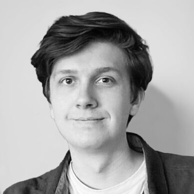 Portrait of a man with medium length hair smiling wearing a t shirt and blazer