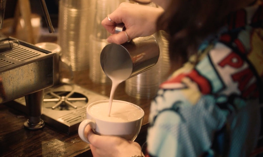 Image of a woman pouring a latte