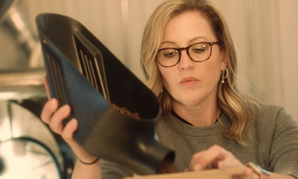 Image of a woman wearing glasses grinding coffee beans