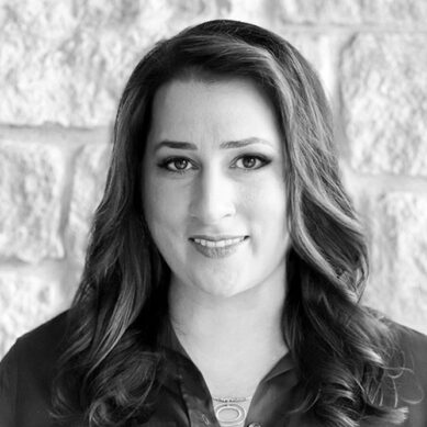 Portrait of a woman with long curled hair against a white brick background