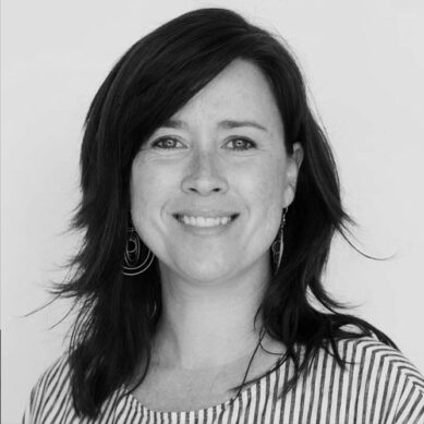 Black and white portrait of a smiling woman with shoulder-length hair and stripped shirt