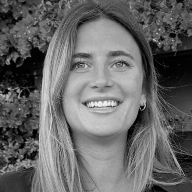 black and white image of woman smiling in front of some bushes wearing hoop earrings